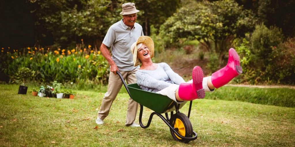 An Old Man Pushing a Wheelbarrow With His Wife in It.