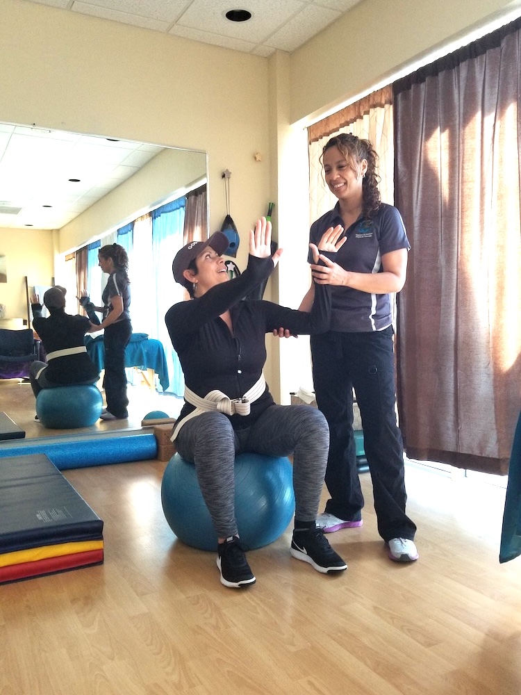 Dr. Evelyn Mora helping a patient improve posture and movement patterns related to upper back pain from desk work in Pembroke Pines