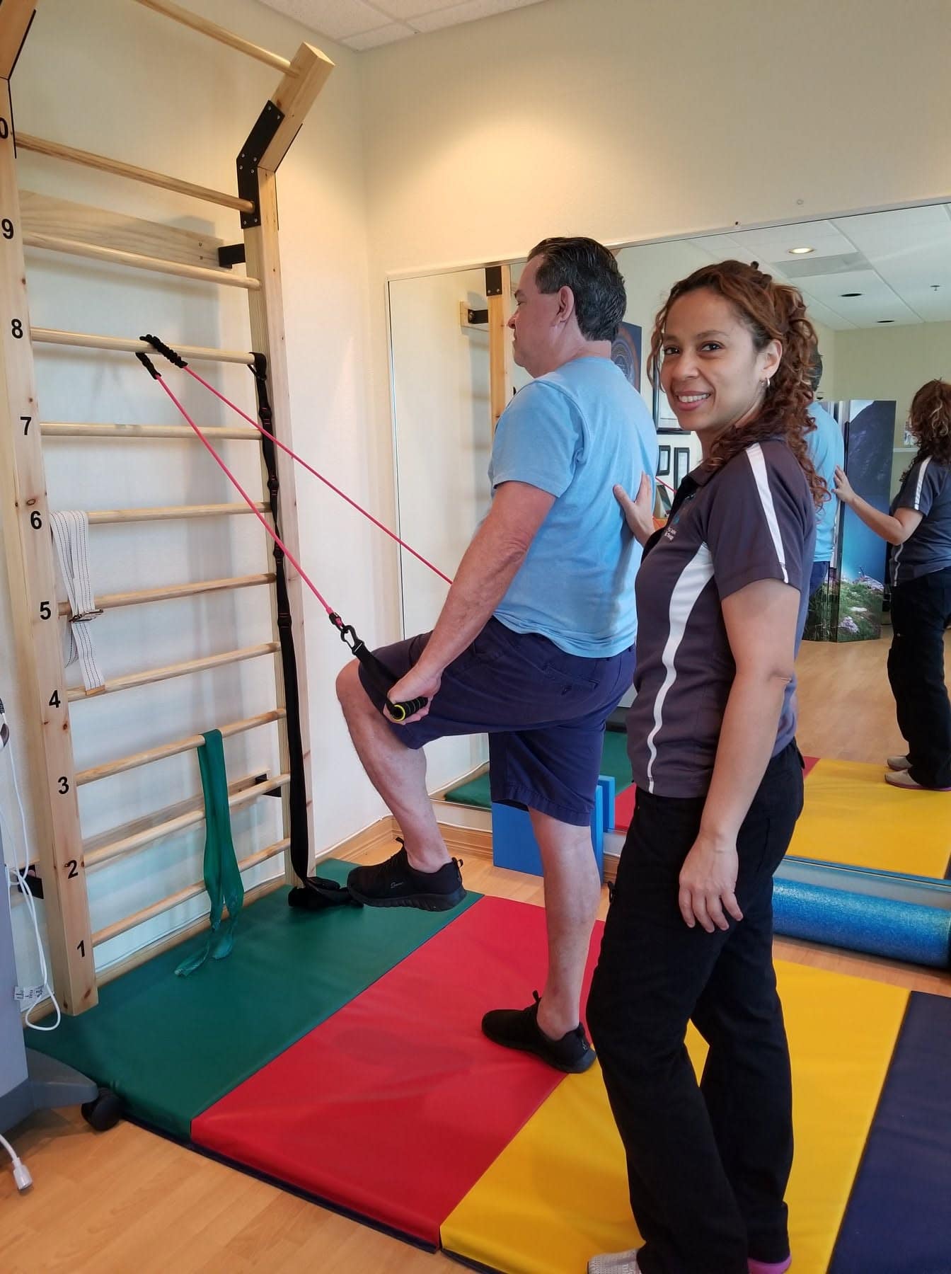 Dr. Evelyn Mora guiding a patient through a standing strengthening exercise at Healers of Motion in Pembroke Pines
