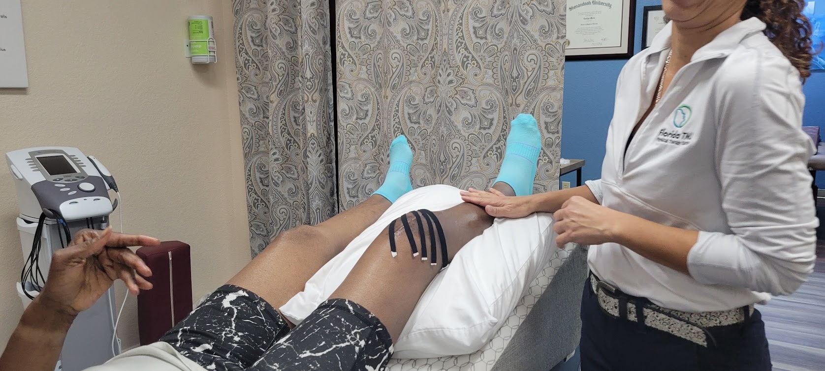 Dr. Evelyn Mora providing hands-on physical therapy for a patient's knee at Healers of Motion in Pembroke Pines