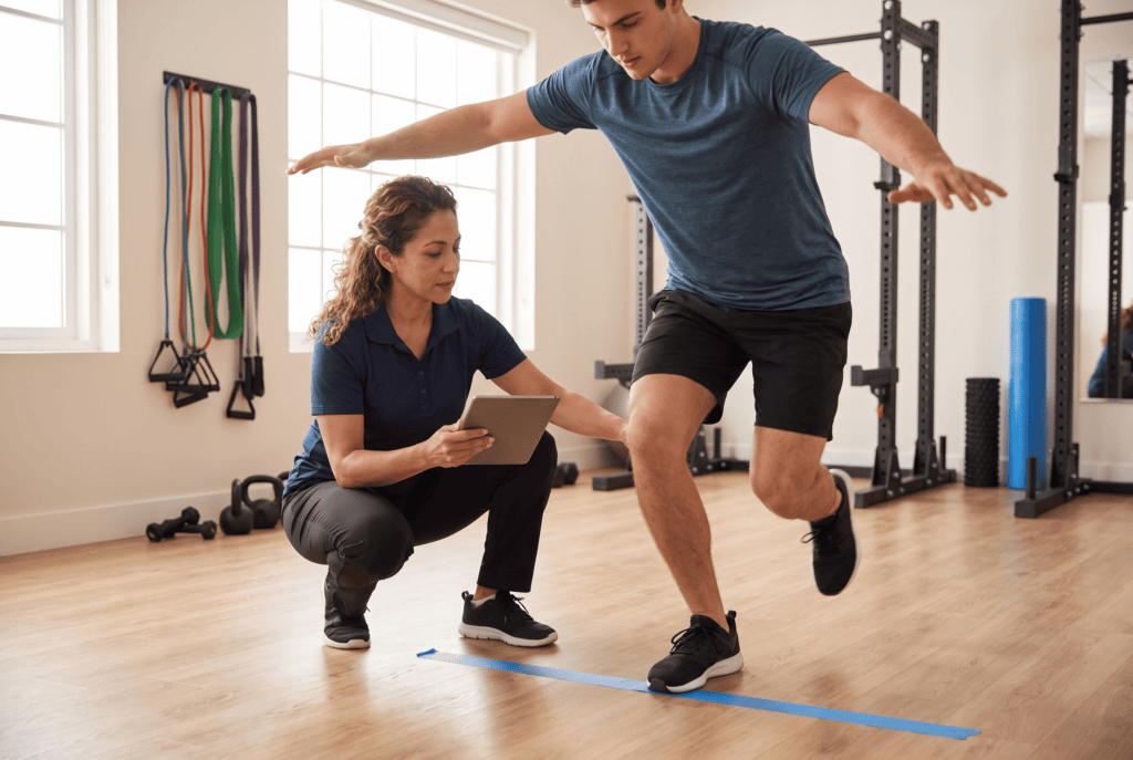 Athlete performing a single-leg hop test during return to play testing while a physical therapist records limb symmetry results